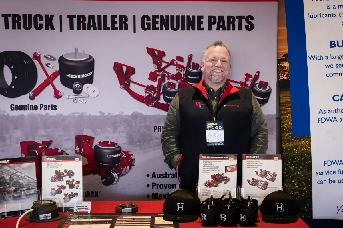 Exhibitor standing behind a truck and trailer parts display at LRTAWA Corporate Event.