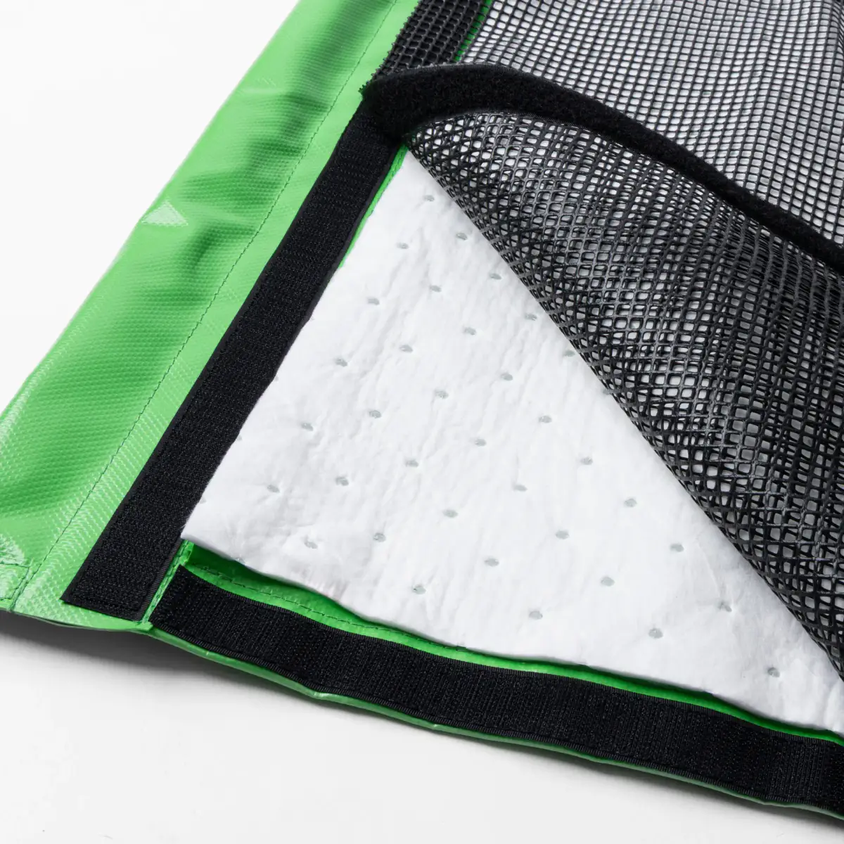 Close-up of the Lubie spill-containment mat showing its green edge, black mesh, and white absorbent layer