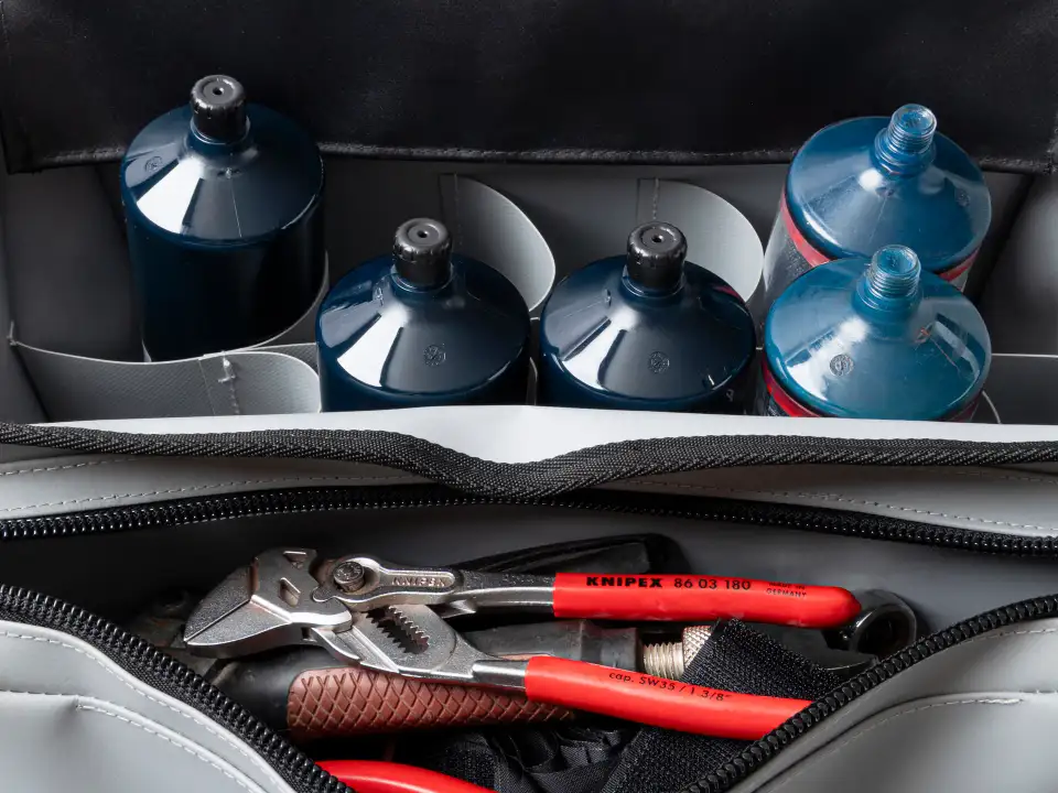 Open Lubie SPL 500 industrial maintenance bag loaded with lubricant cartridges, batteries, and hand tools on a white background