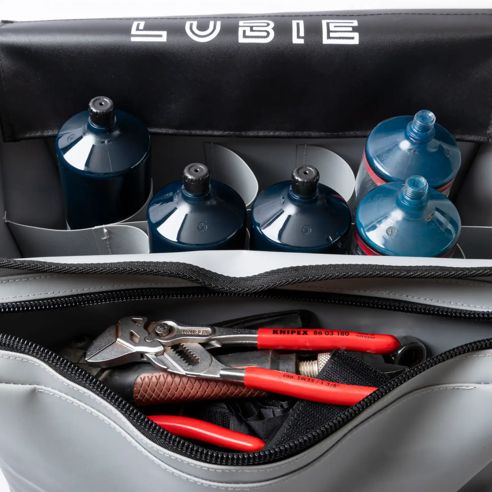 Open Lubie SPL 500 industrial maintenance bag loaded with lubricant cartridges, batteries, and hand tools on a white background