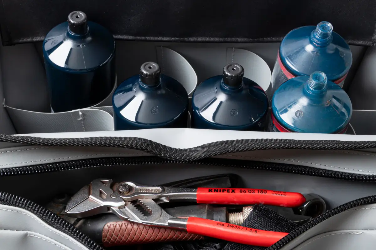 Open Lubie SPL 500 industrial maintenance bag loaded with lubricant cartridges, batteries, and hand tools on a white background