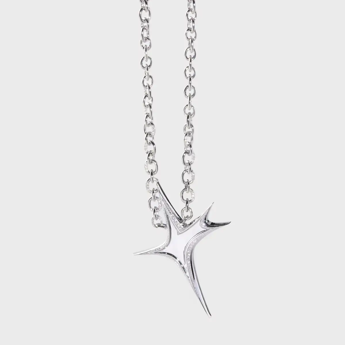 Close-up of a silver diamond-set star pendant and chain showing polished metal detail.