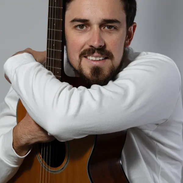 Musician holding an acoustic guitar during a Perth portrait session.