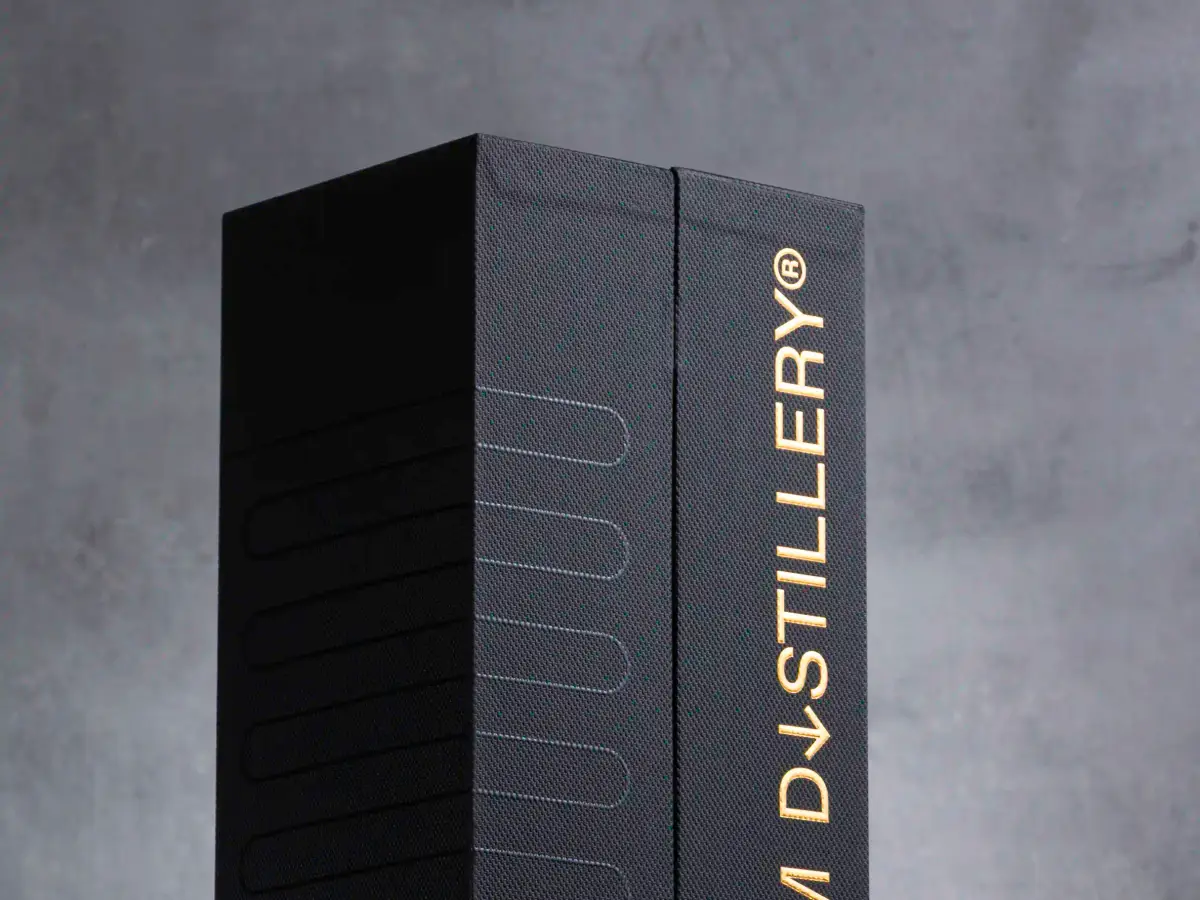 Black Roam Distillery rigid packaging box with gold foil branding photographed upright on a dark studio background
