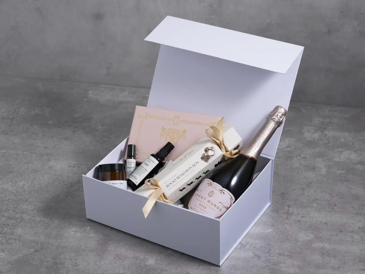 White rigid gift box filled with wine, beauty products, and branded hamper items photographed for Myerton Packaging