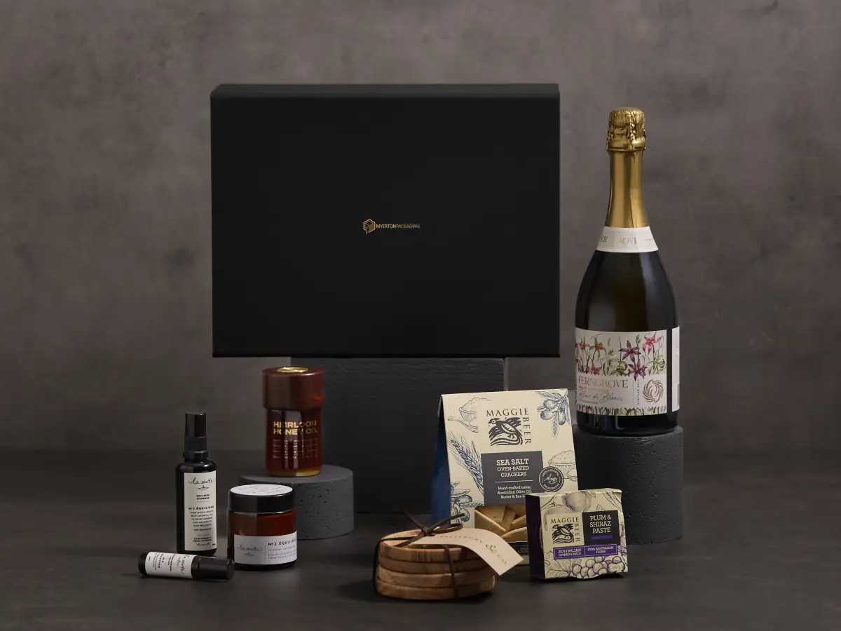 Premium black Myerton Packaging gift box styled with wine, gourmet food, and packaged products on a dark studio set