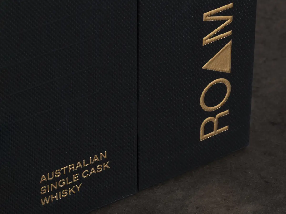 Close-up detail of black textured whisky packaging with gold foil branding