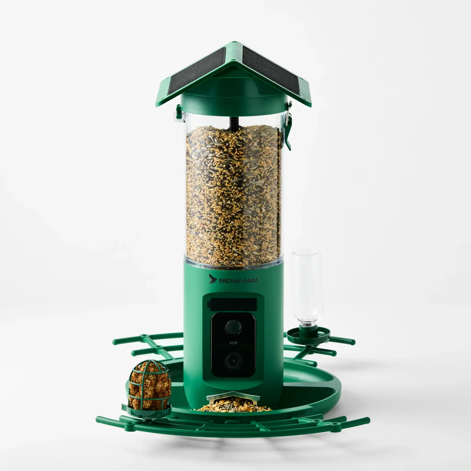 Green Nexavian camera bird feeder filled with seed, with its roof, front camera and feeding attachments visible on a light background