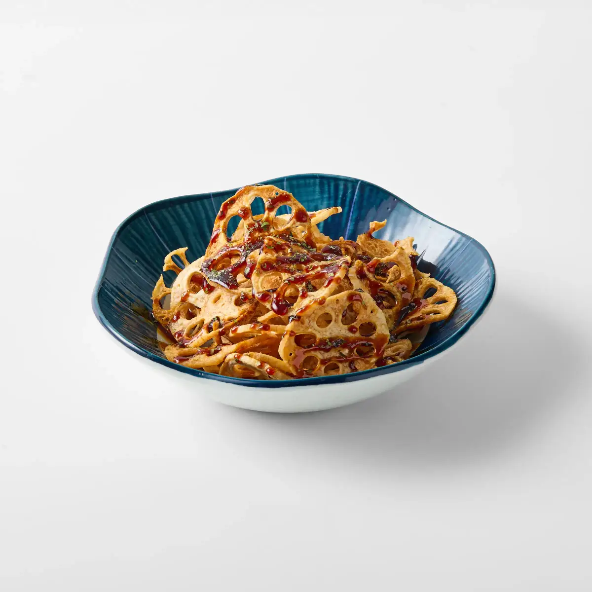 Crisp lotus root chips from Omasa Japanese Restaurant drizzled with sauce in a blue bowl on a white background