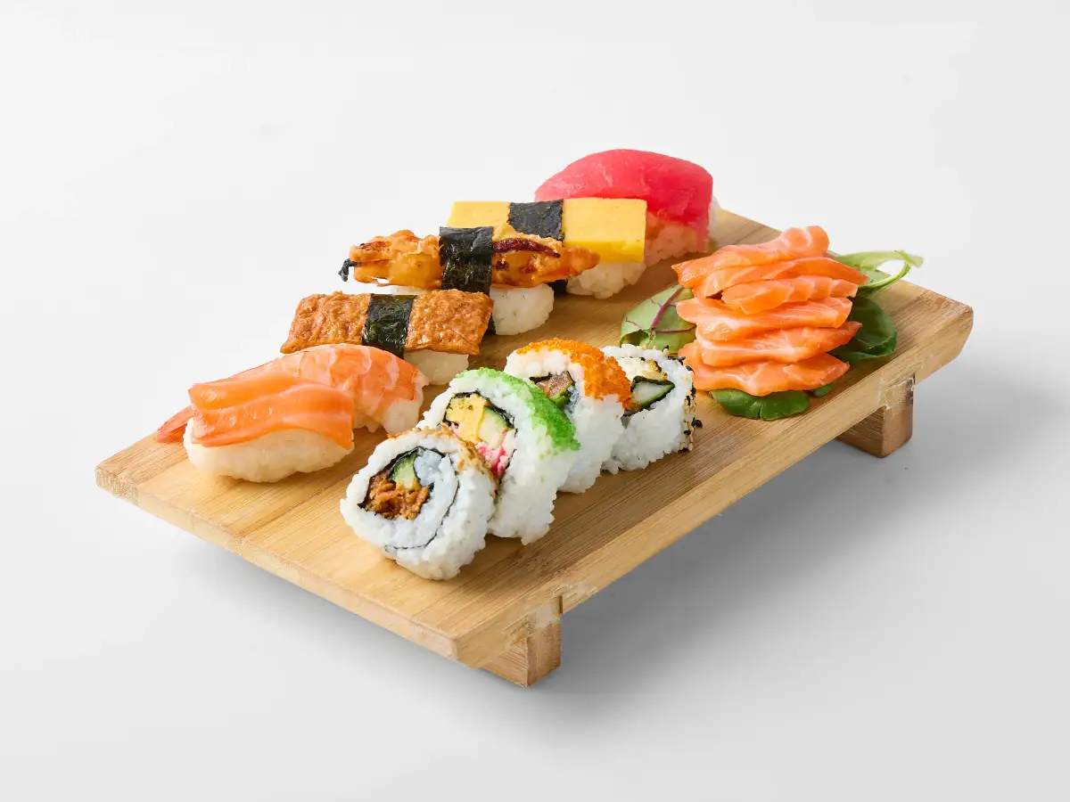 Assorted nigiri, sashimi, and sushi rolls from Omasa Japanese Restaurant arranged on a timber board against a white background