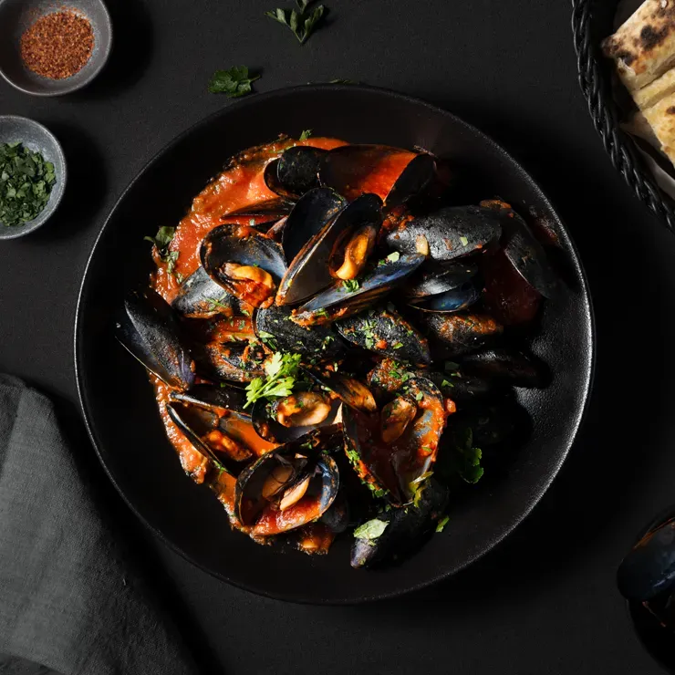 Top-down flat lay food photography of gourmet mussels, styled effectively for restaurant website headers and social media.
