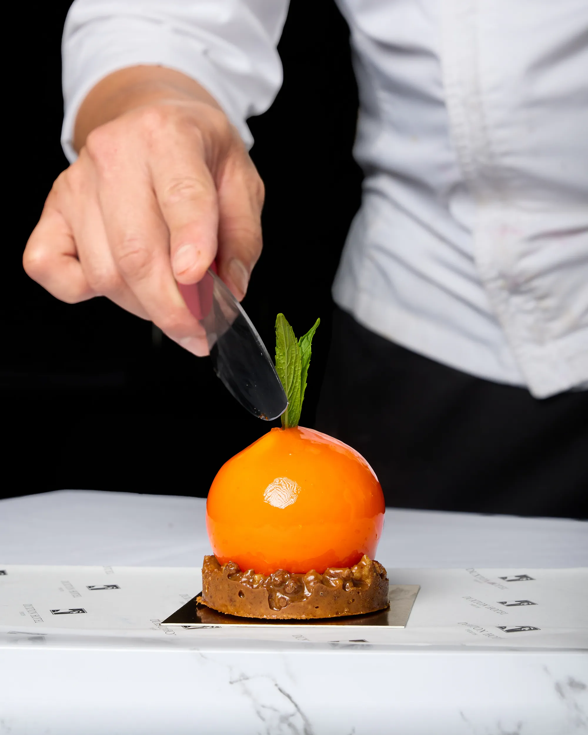 Chef finishing a plated orange dessert at Duxton Hotel Perth