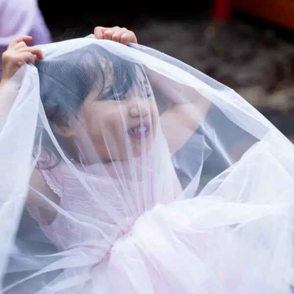 Child playing with a veil during a relaxed birthday portrait moment.