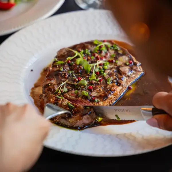 High-contrast close-up of a steak being cut, professional menu photography for Perth steakhouses.