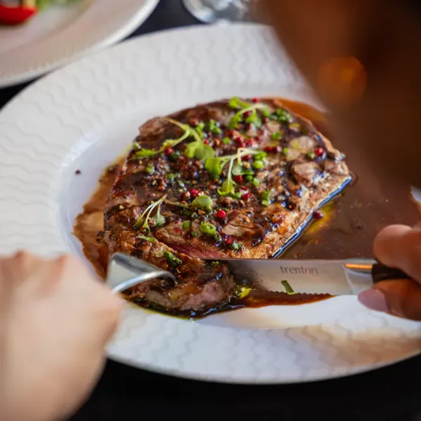 High-contrast close-up of a steak being cut, professional menu photography for Perth steakhouses.