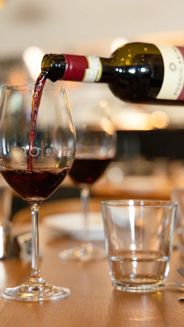 Red wine being poured at a restaurant table, lifestyle winery photography for Perth cellar doors.