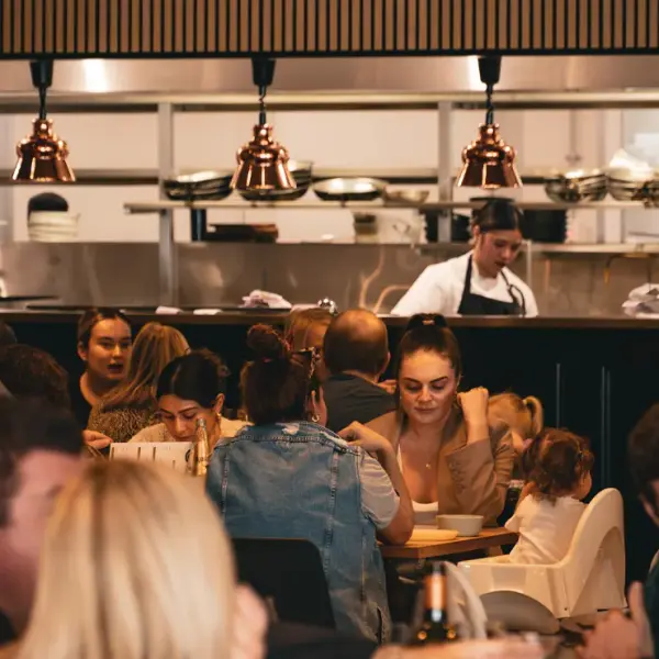Wide angle shot of a busy Perth restaurant interior with an open kitchen, high-quality asset for venue website development.