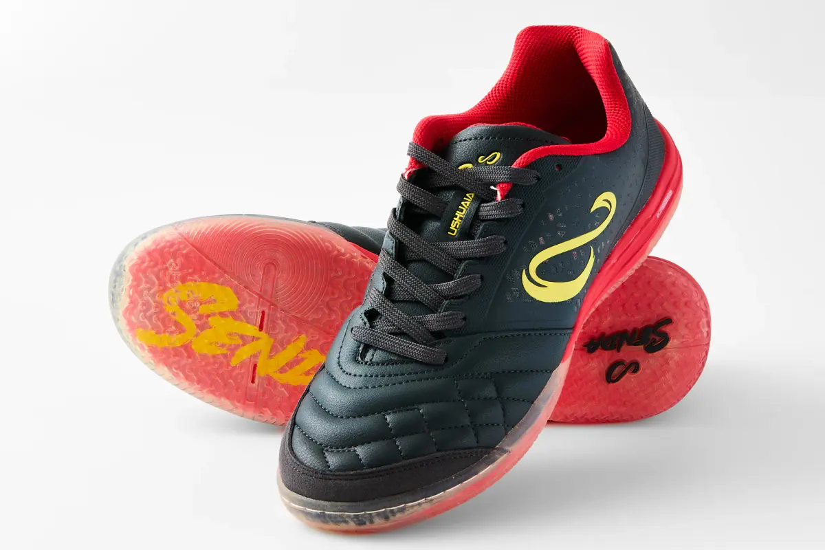 Black and red Senda Ushuaia futsal shoes arranged to show the upper and translucent red sole on a white ecommerce background