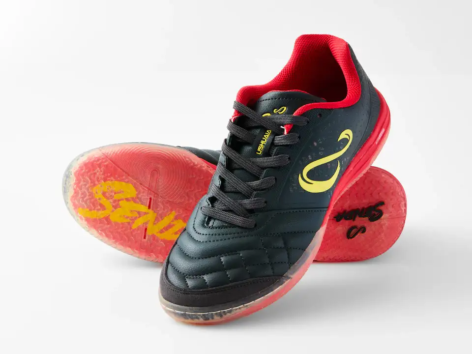 Black and red Senda Ushuaia futsal shoes arranged to show the upper and translucent red sole on a white ecommerce background