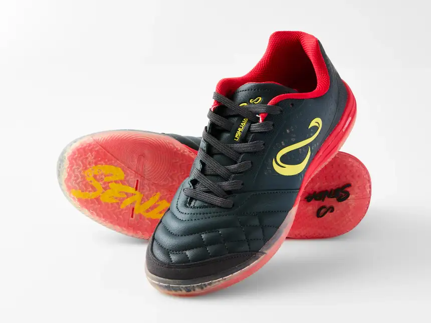 Black and red Senda Ushuaia futsal shoes arranged to show the upper and translucent red sole on a white ecommerce background