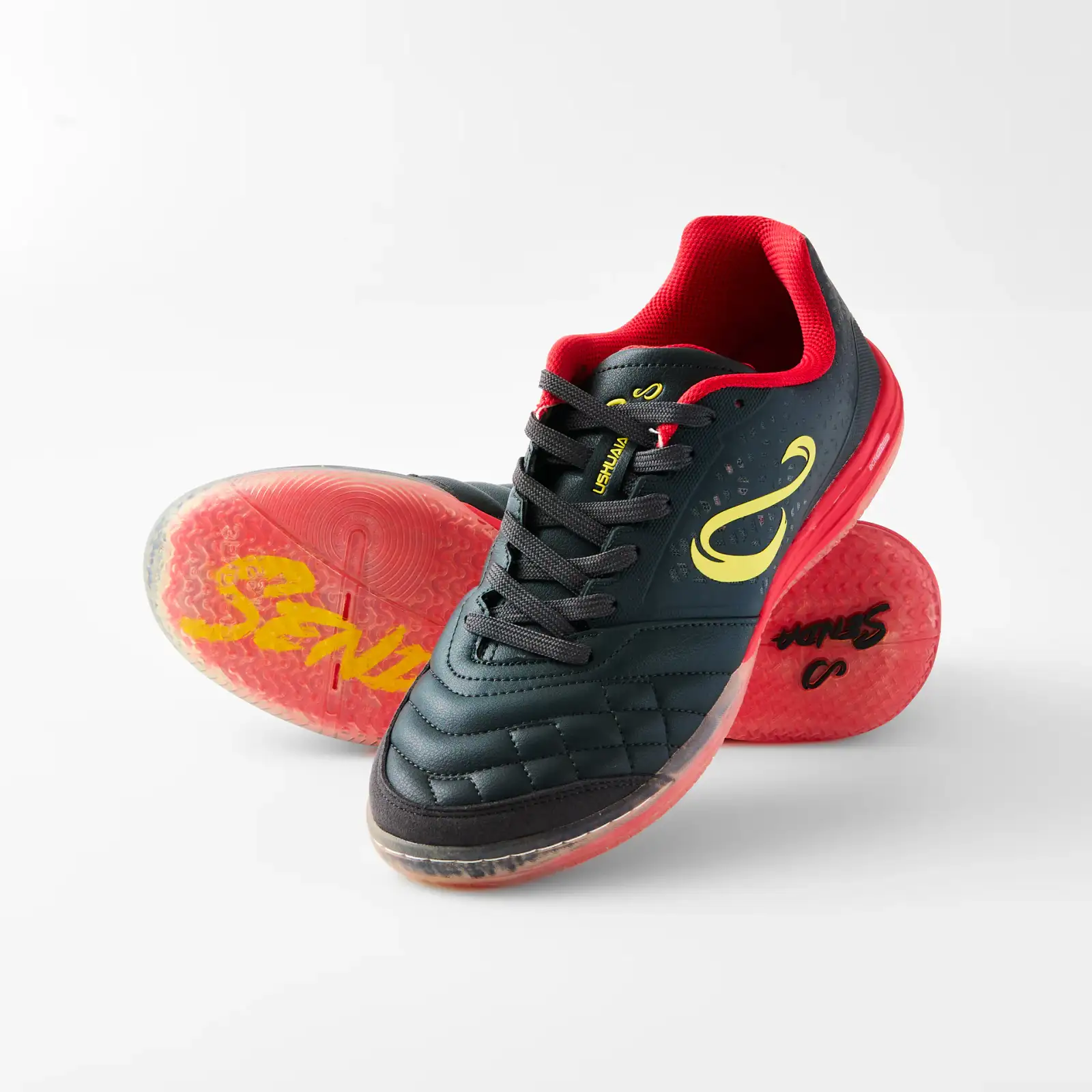 Black and red Senda Ushuaia futsal shoes arranged to show the upper and translucent red sole on a white ecommerce background