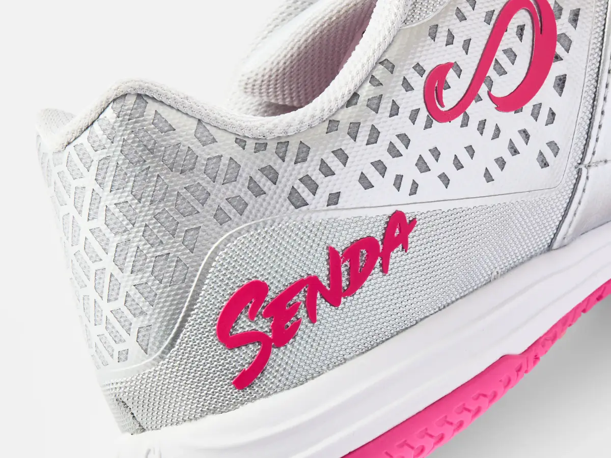 Close-up of the silver and pink Senda Ushuaia futsal shoe showing the perforated upper, side logo, and textured materials