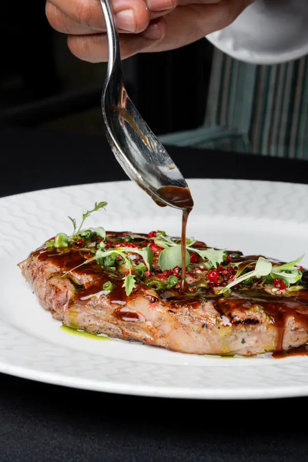 Sauce being poured over a steak, dramatic action shot for bar and grill photography in Perth.