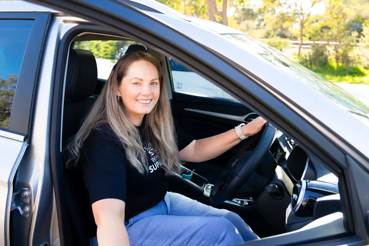 Stroke survivor Karla smiling from the driver's seat of her car, representing independence after stroke