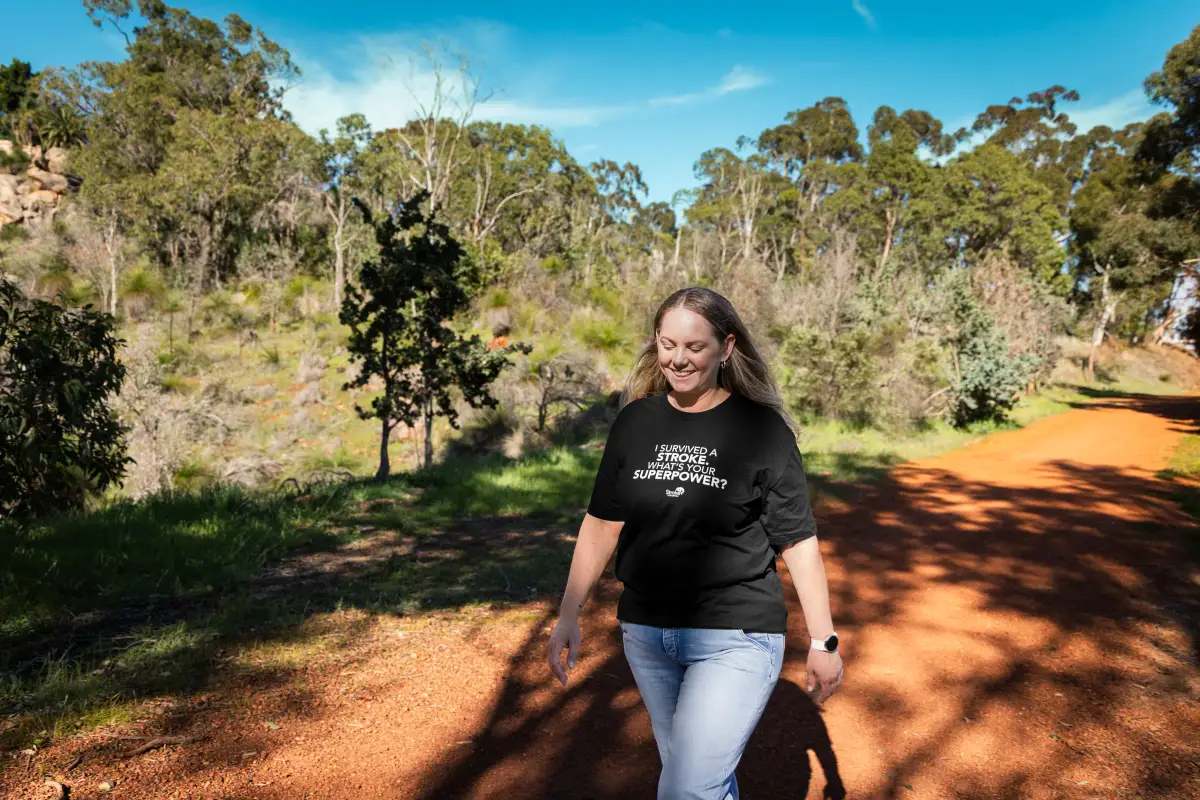 Stroke survivor Karla walking along a sunlit bush track during a recovery and awareness photography session