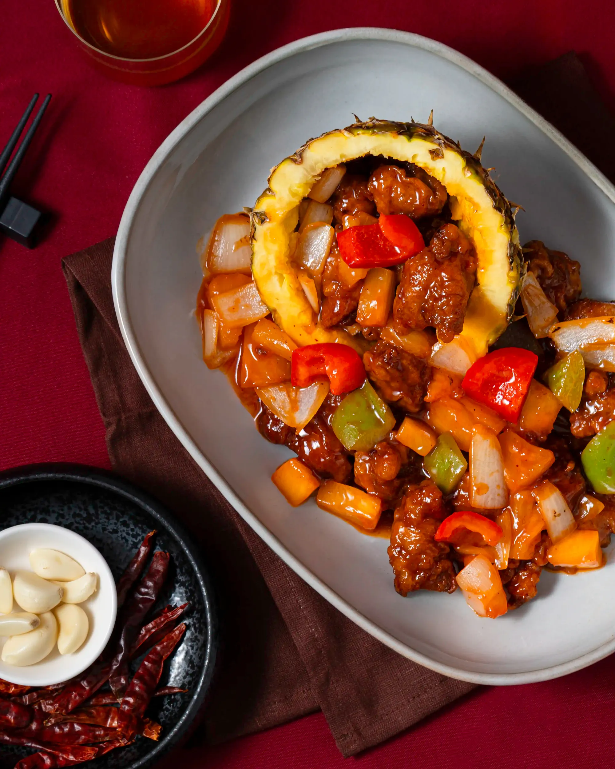 Sweet and sour pork with capsicum served on a red table
