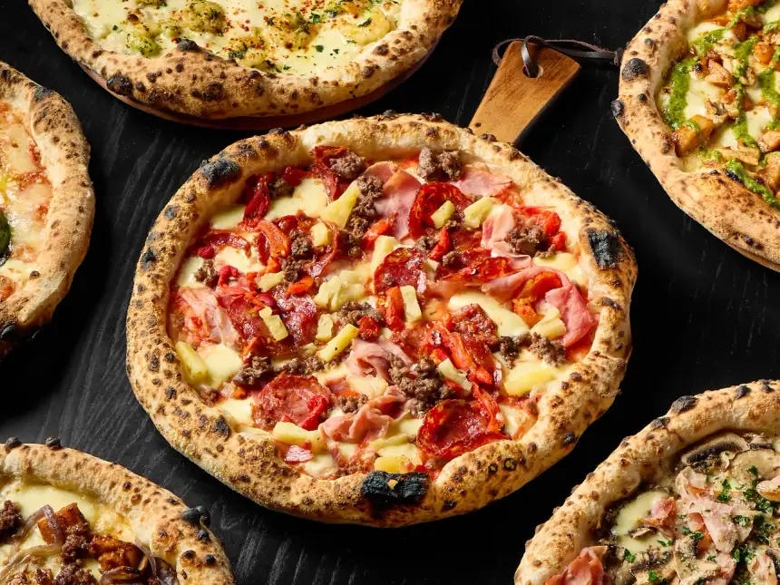Freshly baked artisan pizzas and gourmet paninis from The Good Pizza in Myaree arranged on dark surface for Uber Eats and menu marketing