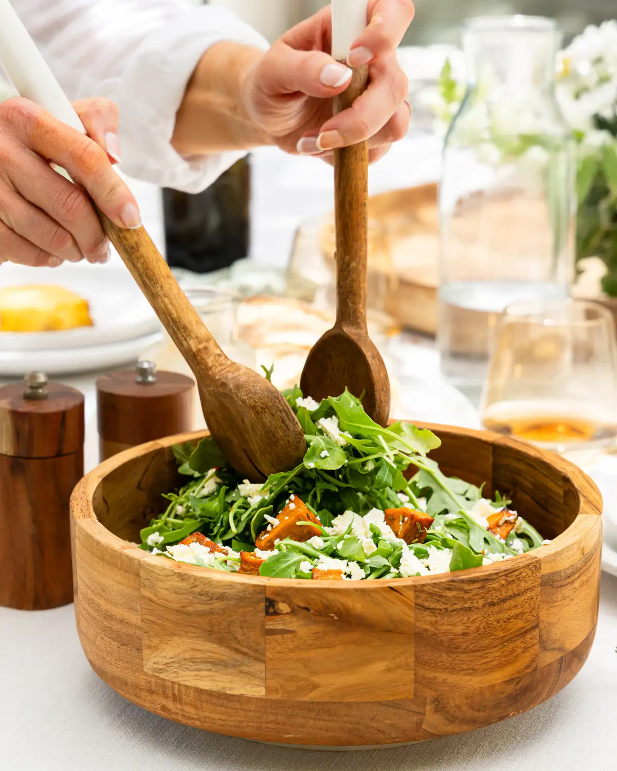 Fresh salad tossed with wooden utensils to show product use and movement.