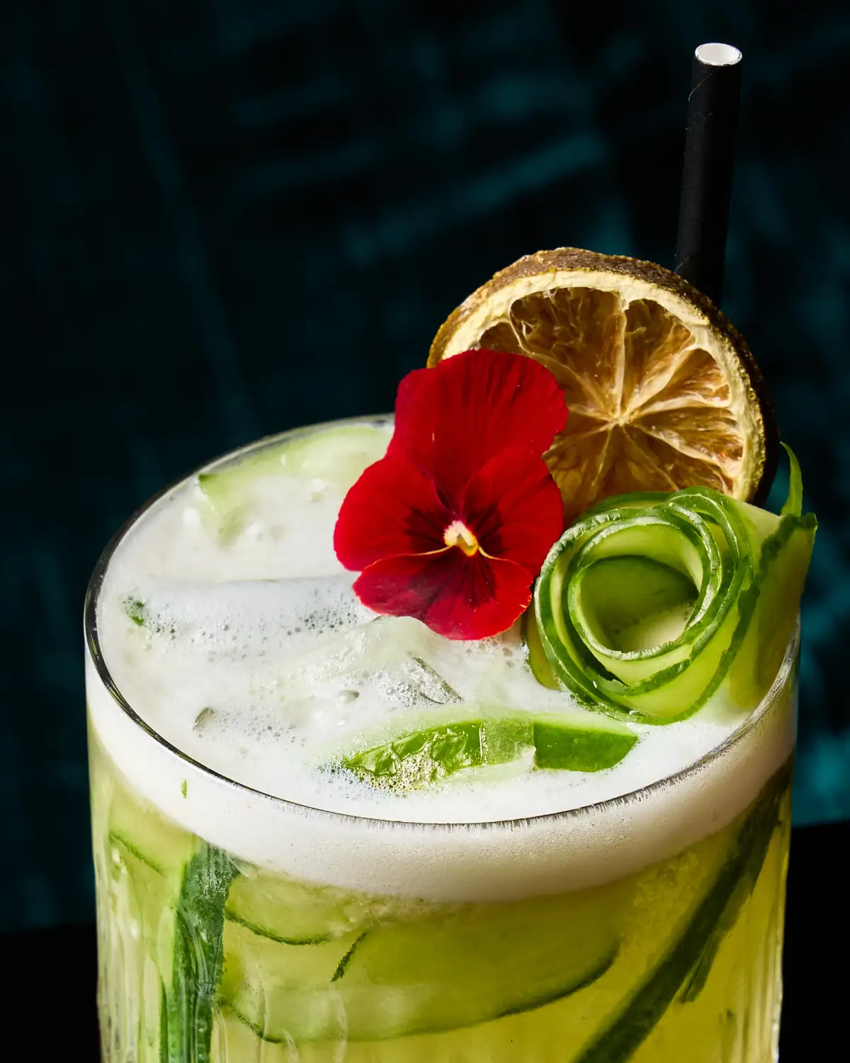 Green cucumber and lime cocktail at T.O.T.O Bar with foam, flower garnish, and dehydrated citrus