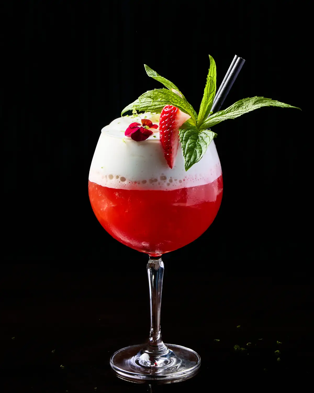 Red raspberry cocktail at T.O.T.O Bar with foam, rosemary, raspberry, and a dark studio background