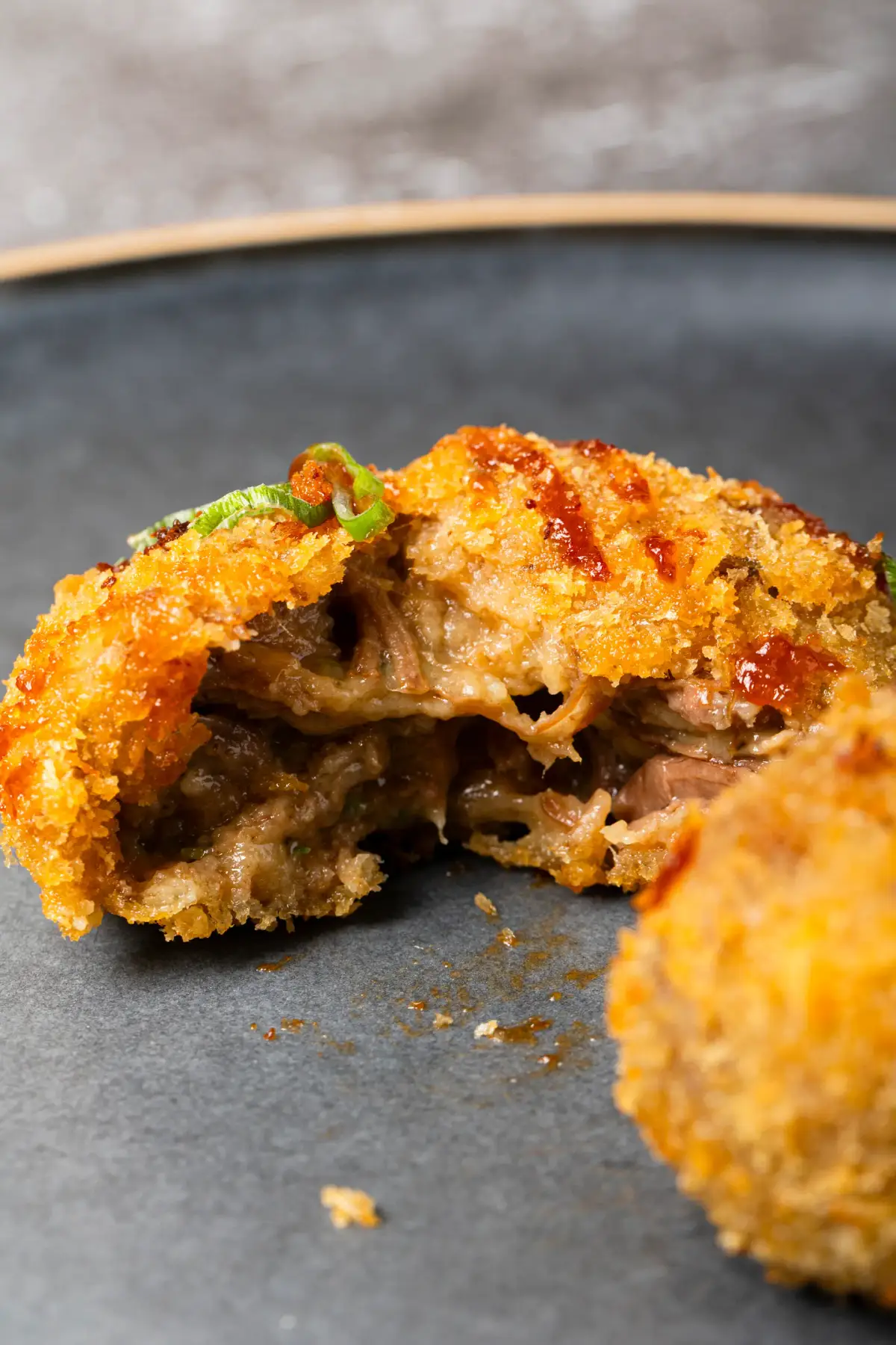 Uai Mate beef ribs croquete broken open to show pulled meat filling with spicy BBQ sauce and spring onion garnish