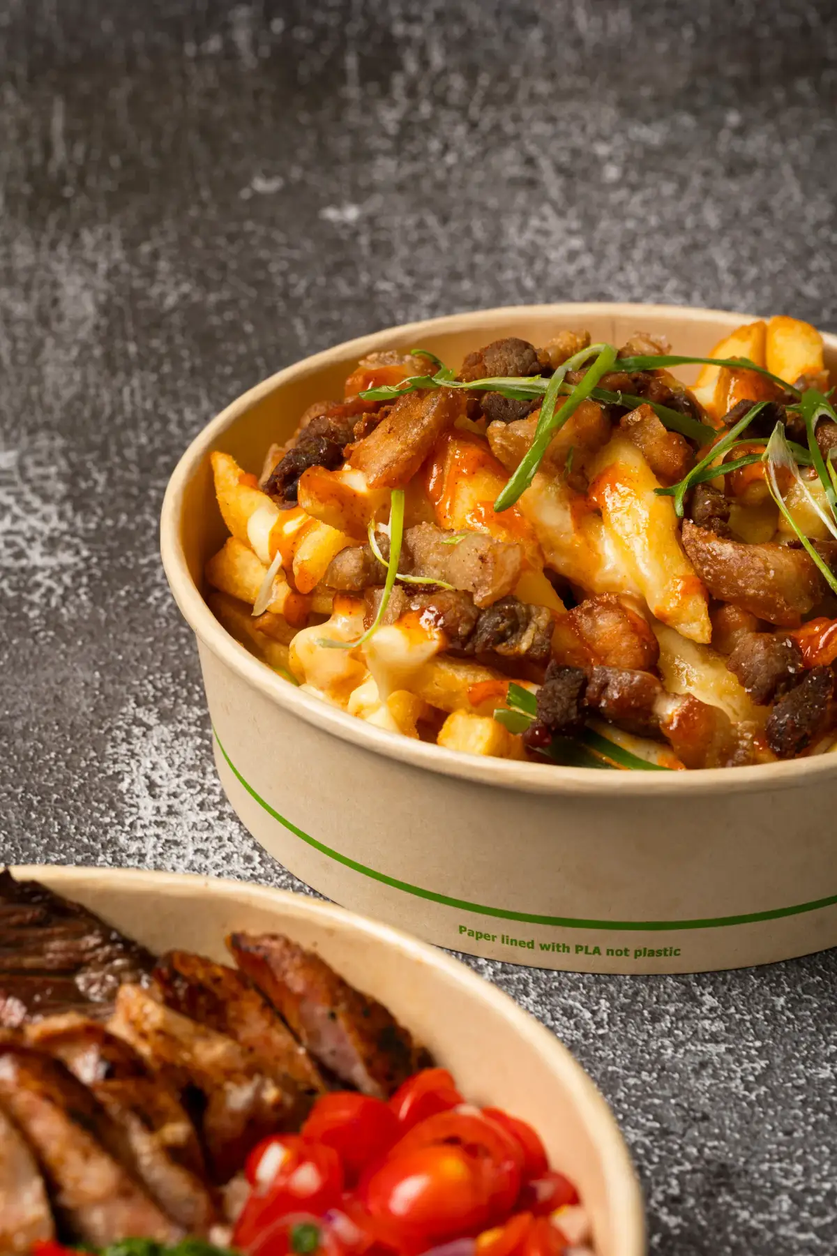 Close-up of Uai Mate holy crack fries loaded with crispy pork belly, melted cheese, chipotle mayo, and spring onions