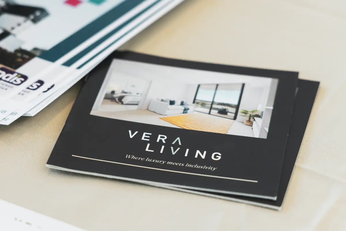 Close-up of a Vera Living brochure on a table showing the brand name and interior imagery