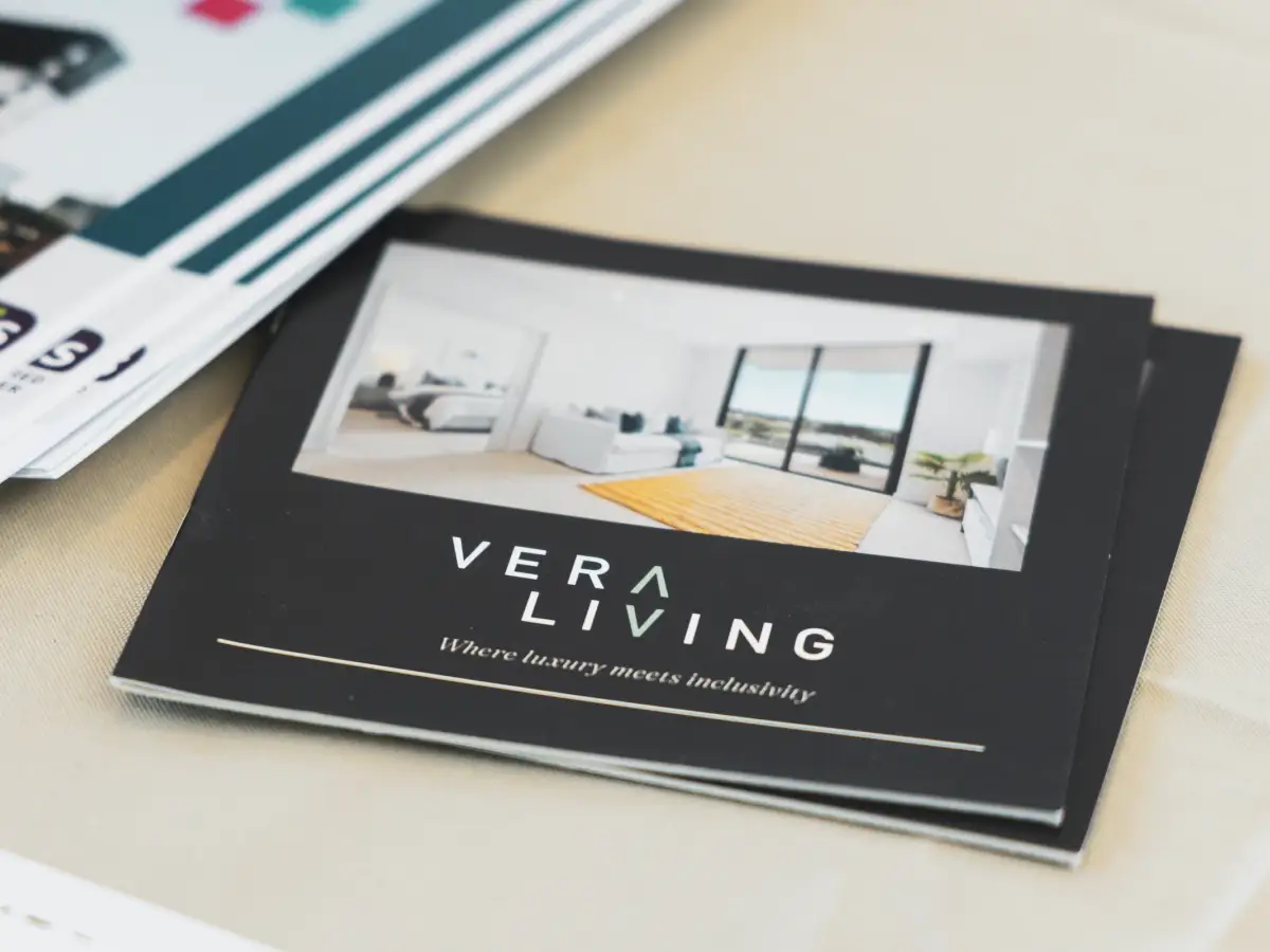 Close-up of a Vera Living brochure on a table showing the brand name and interior imagery