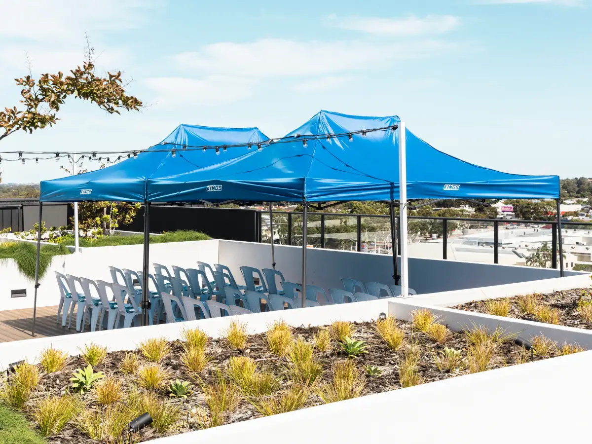 Blue event marquees and rows of white chairs set up on a rooftop terrace for a Vera Living event in Cannington