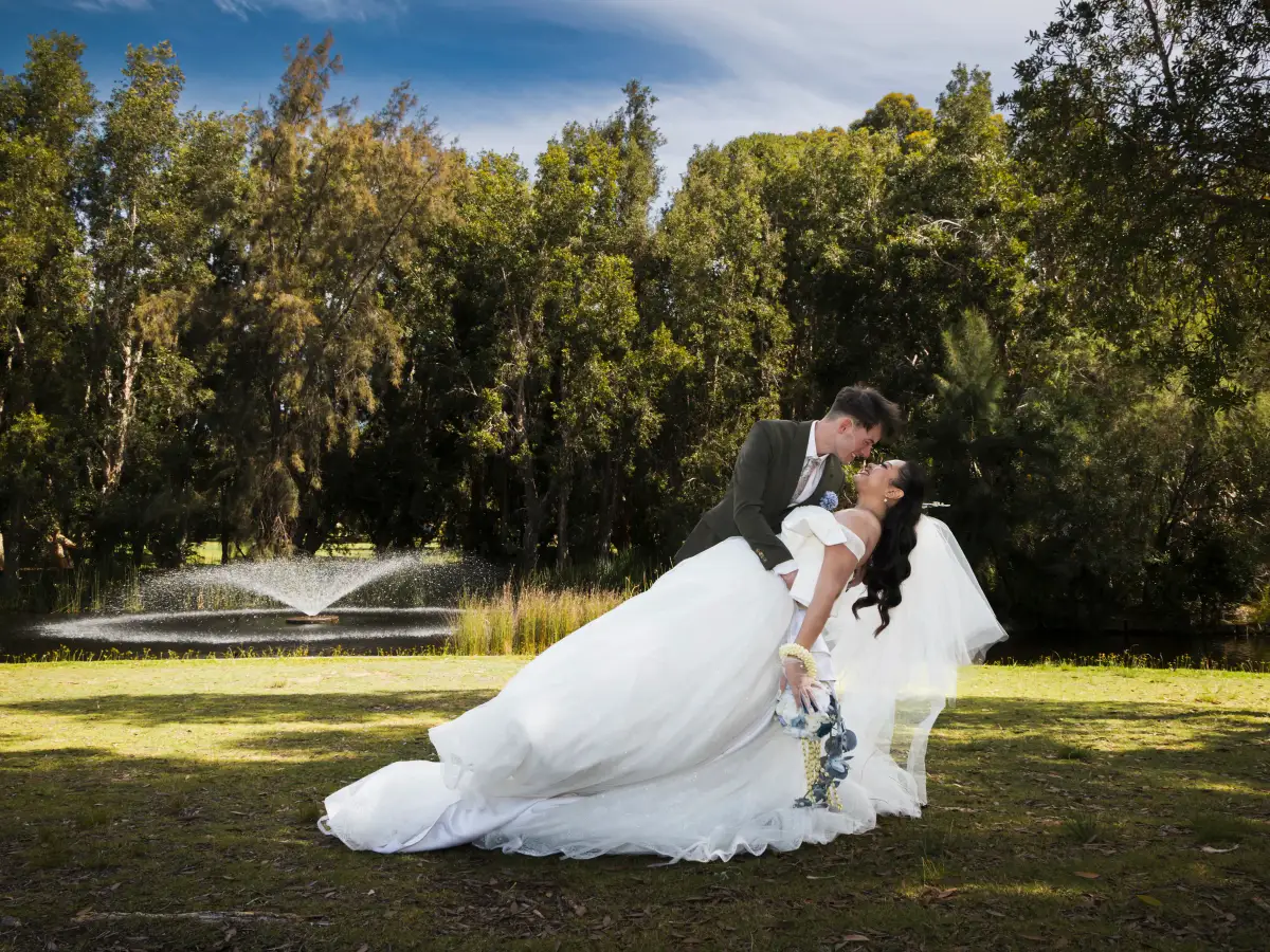 Bride and groom sharing a dip kiss beside the lake at Piney Lakes Reserve after their wedding ceremony