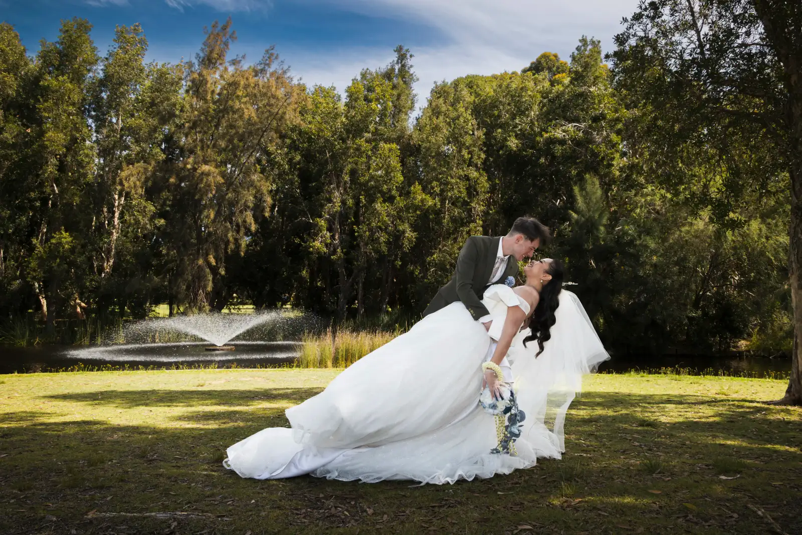 Bride and groom sharing a dip kiss beside the lake at Piney Lakes Reserve after their wedding ceremony