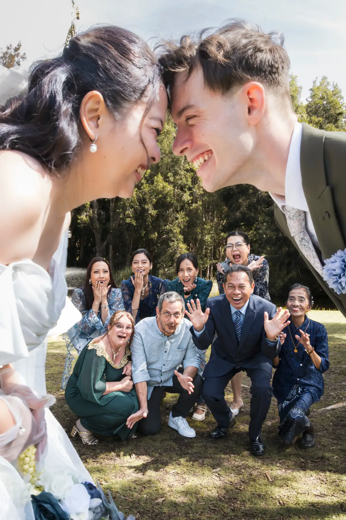 Wedding couple surrounded by family reactions during portraits after the ceremony