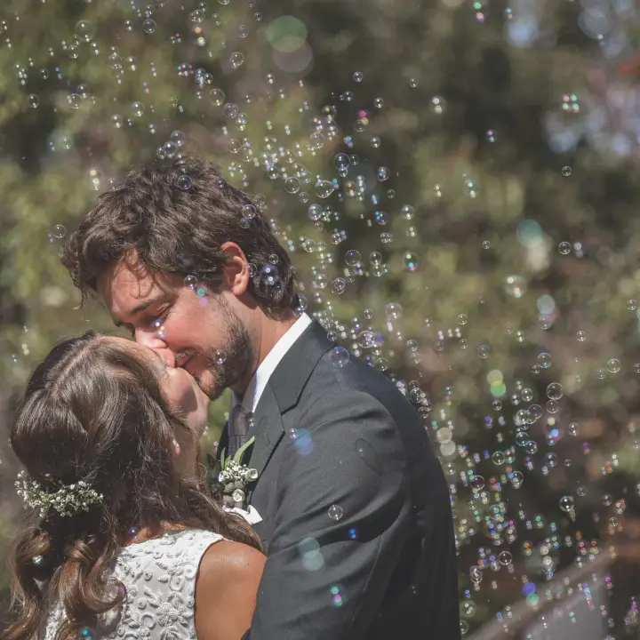 Bride and groom kissing beneath bubbles during a Perth wedding celebration.