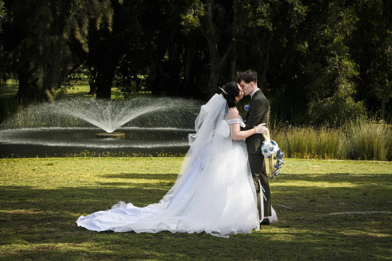 Wedding couple kissing beside a fountain during an outdoor Perth portrait session.