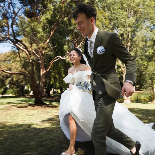 Wedding couple running together through a park during a candid portrait session.